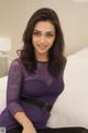 A woman in a purple top sitting on a bed.
