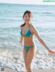 A woman in a blue bikini standing on the beach.