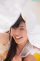 A woman in a white shirt and a straw hat smiles at the camera.