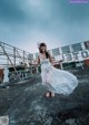 A woman in a white dress standing on top of a roof.