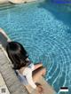 A woman sitting on the edge of a swimming pool.