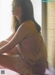 A woman sitting on the floor in front of a window.