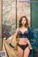 A woman in a blue bra and black panties posing for a picture.