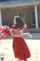 A woman in a red dress is holding a plaid blanket.