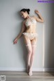 A woman in a white lingerie leaning against a wall.