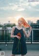 A woman in a black dress holding a flower.